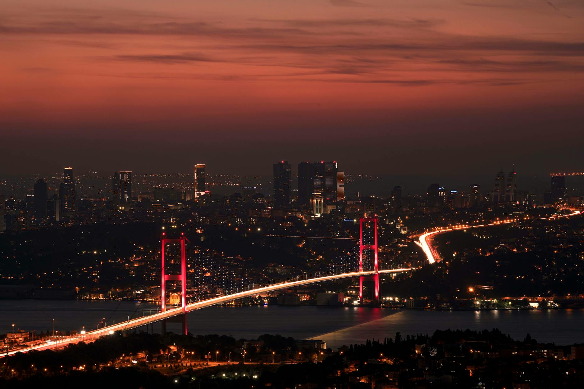 Espectacular vista nocturna del puente del Bósforo iluminado bajo un cielo al atardecer.