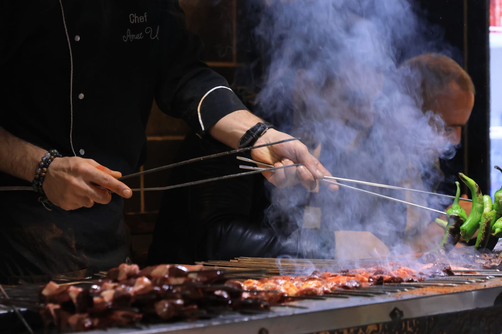 Cocinero preparando brochetas de carne frente a clientes en un ocakbasi.