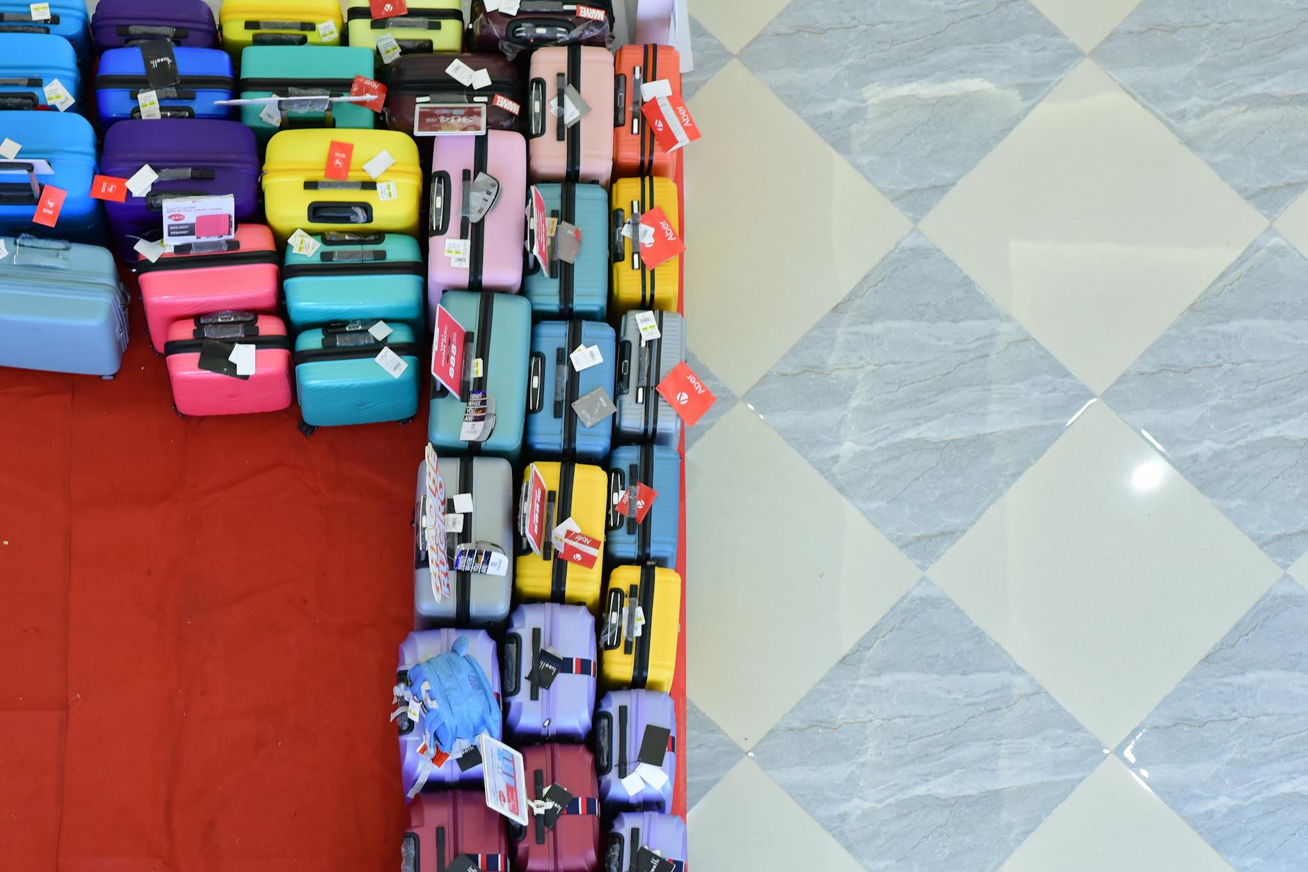 Vista aérea de numerosas maletas de colores guardadas en un suelo de baldosas claras.