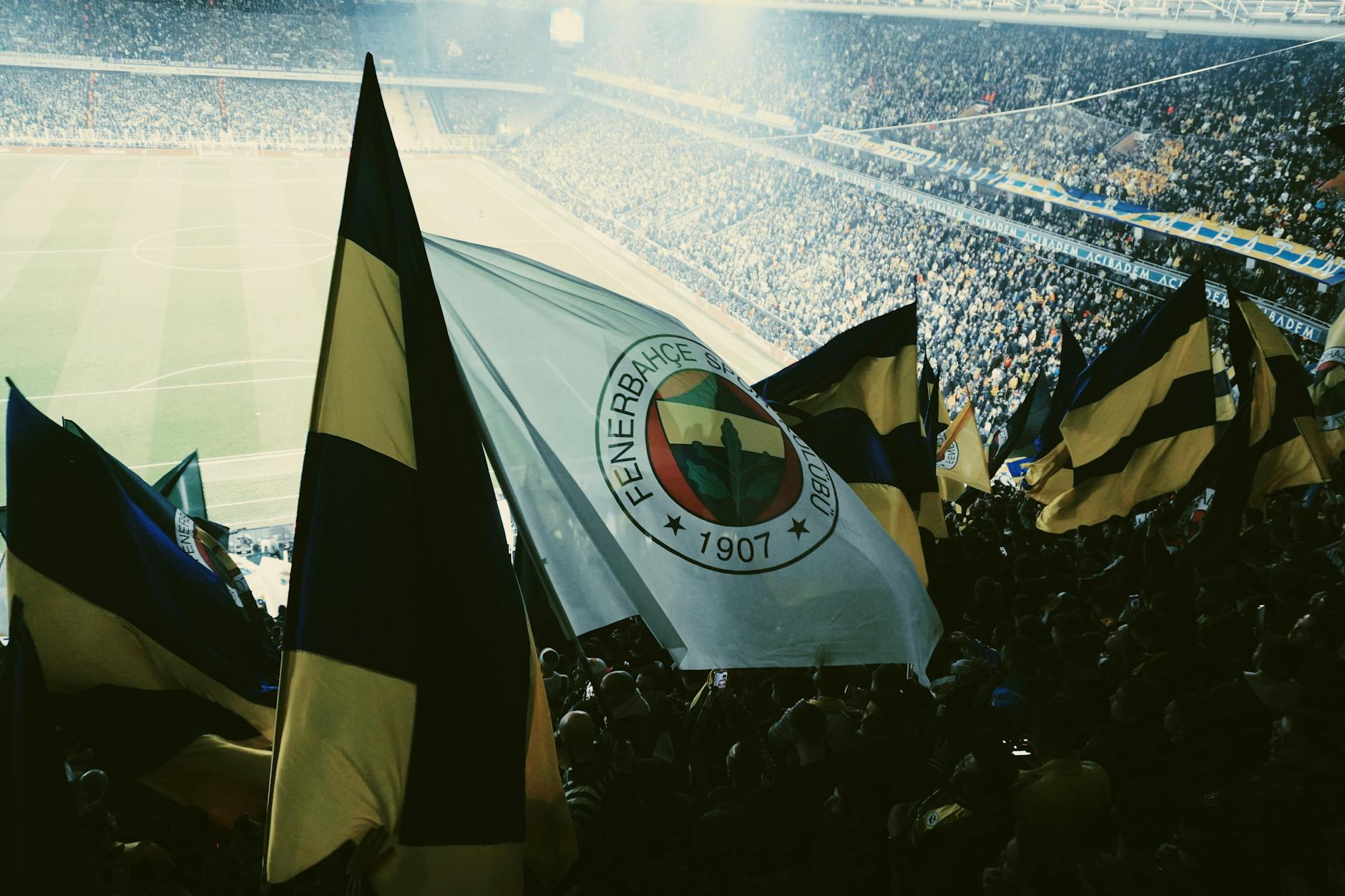 Aficionados del Fenerbahçe ondean banderas durante un partido de fútbol en un estadio de Estambul.