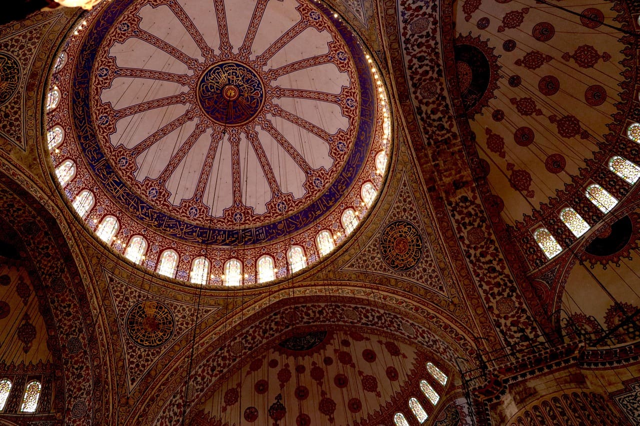 Interior de la cúpula decorada con patrones islámicos y ventanas iluminadas.