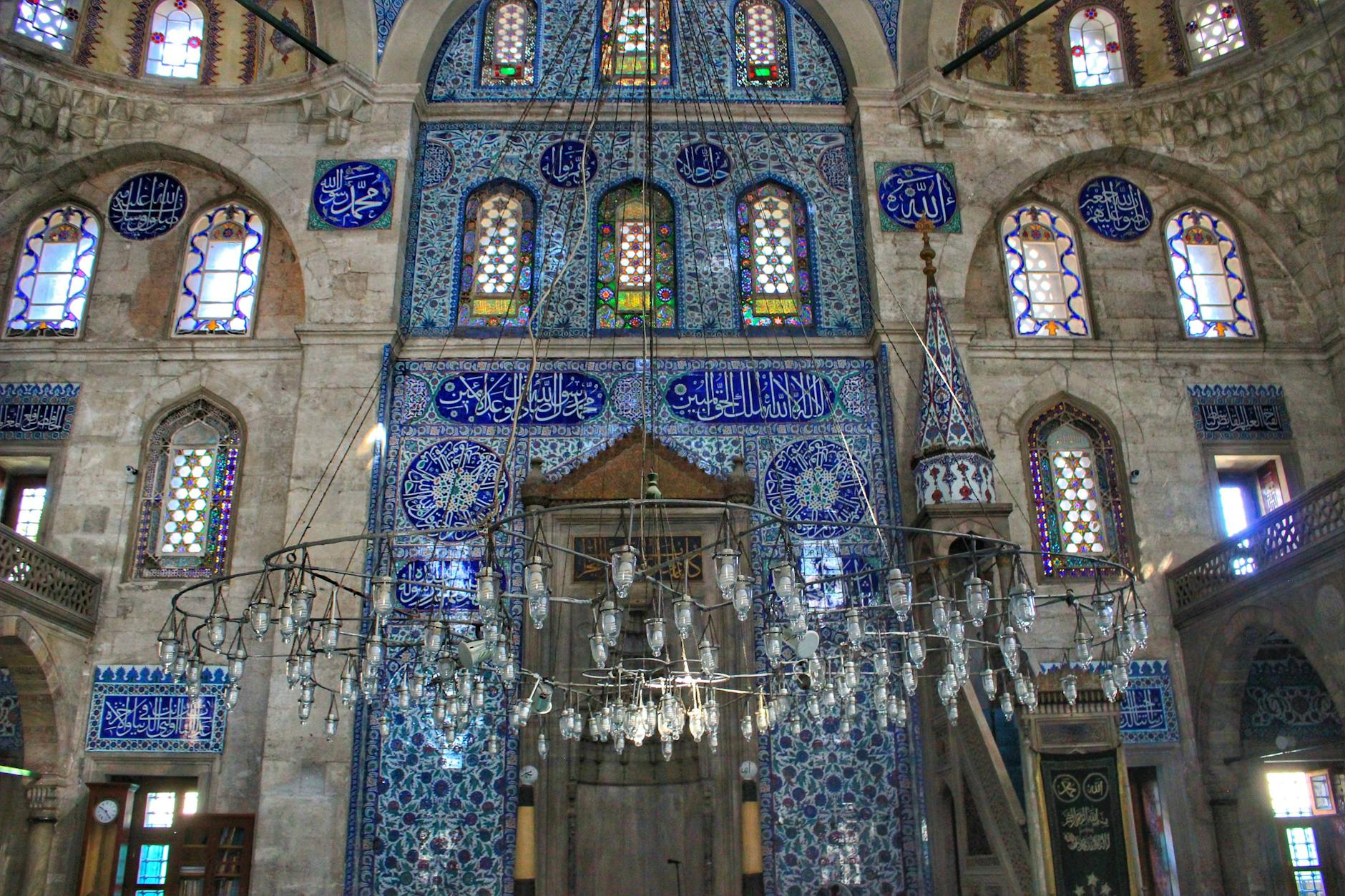 Interior de la Mezquita de Rüstem Paşa en Estambul, destacando las paredes cubiertas con azulejos azules de Iznik y un gran candelabro central.