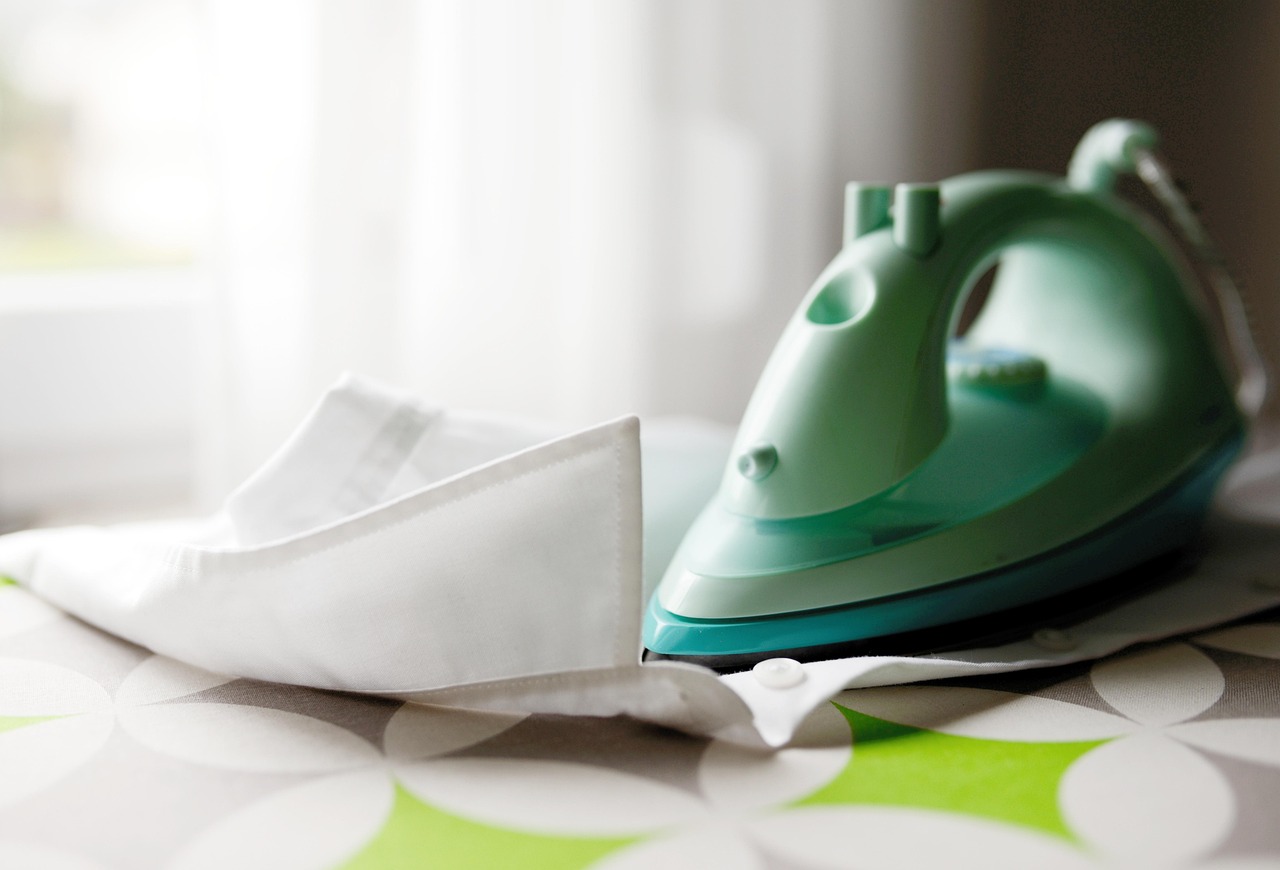 Plancha verde sobre una camisa blanca recién lavada en un servicio de tintorería profesional.
