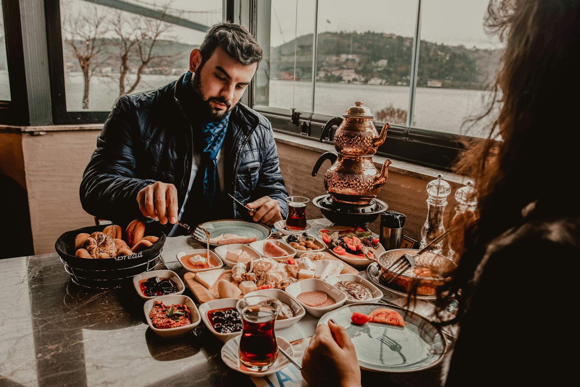 Pareja disfrutando de un tradicional desayuno turco (serpme kahvaltı) con una espectacular vista al Bósforo en Estambul.