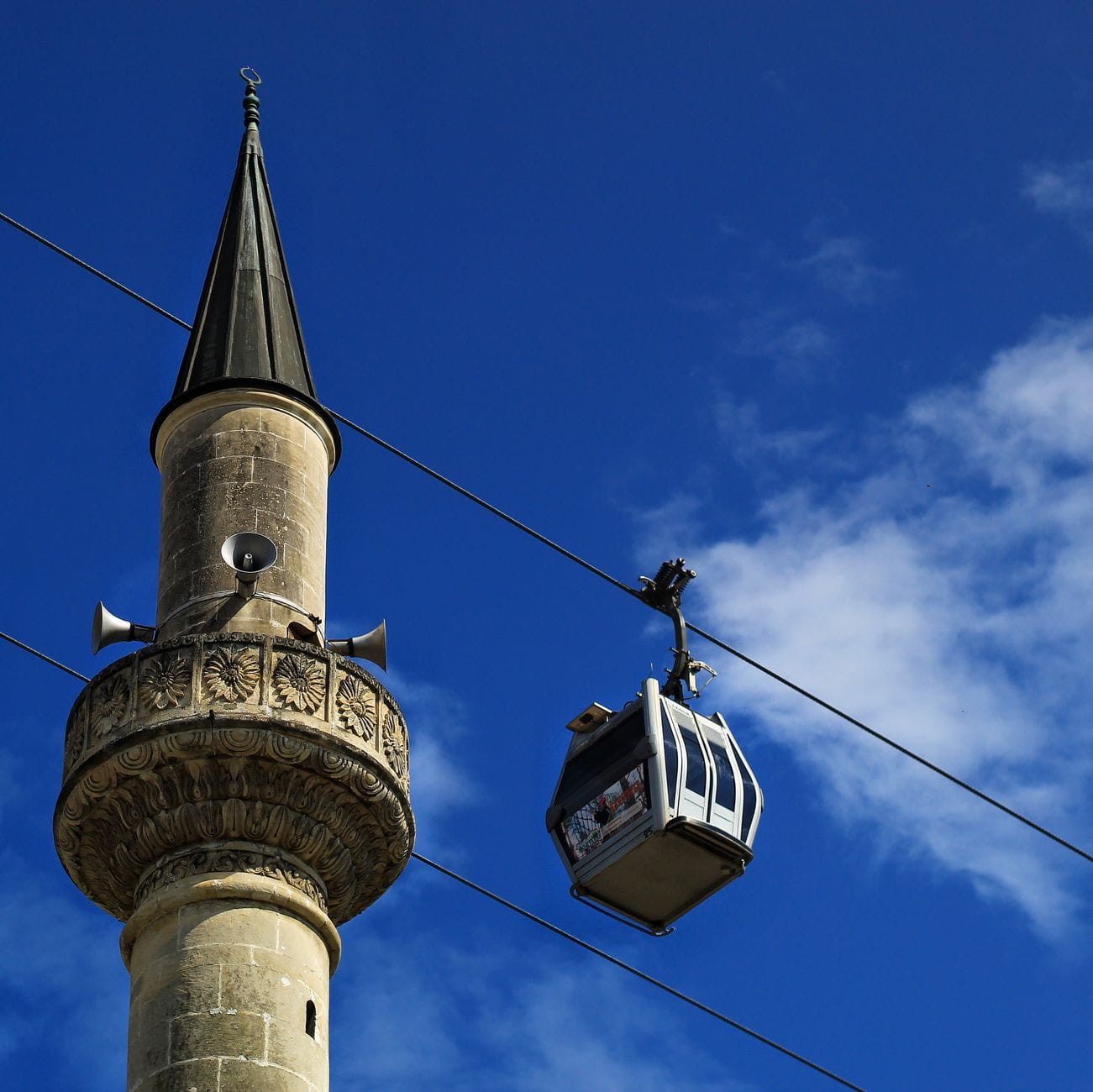 Cabina del teleférico de Estambul sobrevolando cerca de un minarete tradicional.