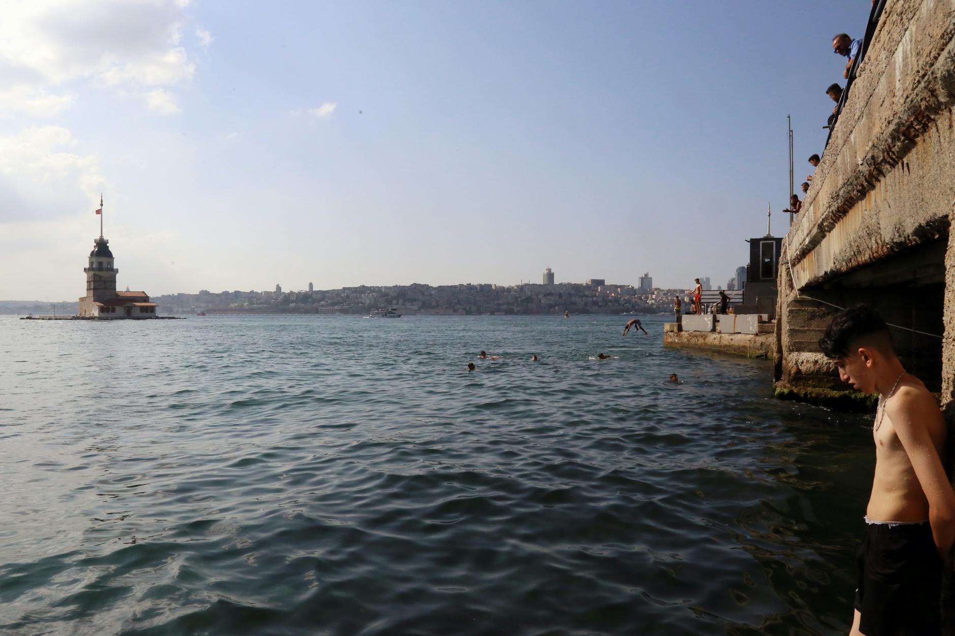 Vista del Bósforo con gente bañándose cerca de la icónica Torre de Leandro de Estambul.