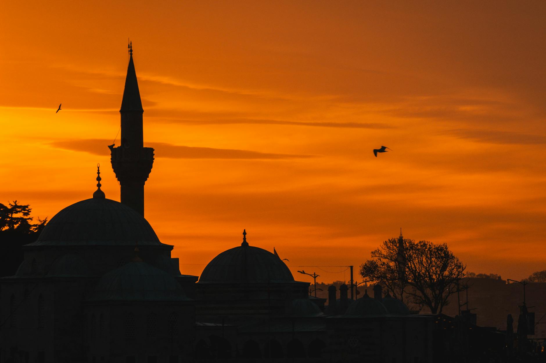 Silueta de una mezquita en Estambul bajo un cielo naranja durante el atardecer.