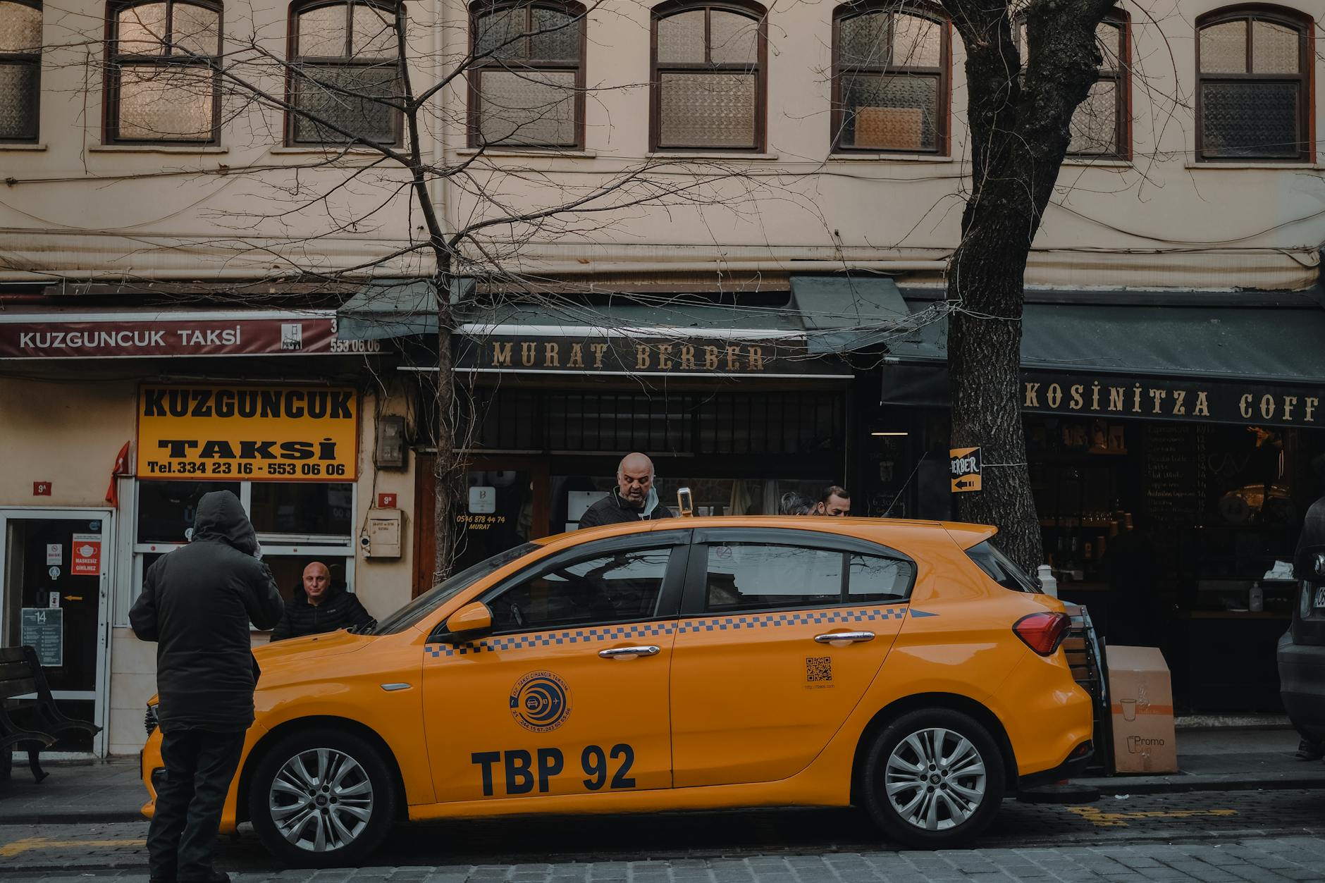 Taxi amarillo de Kuzguncuk con letreros de negocios locales en una calle de Estambul, Turquía.