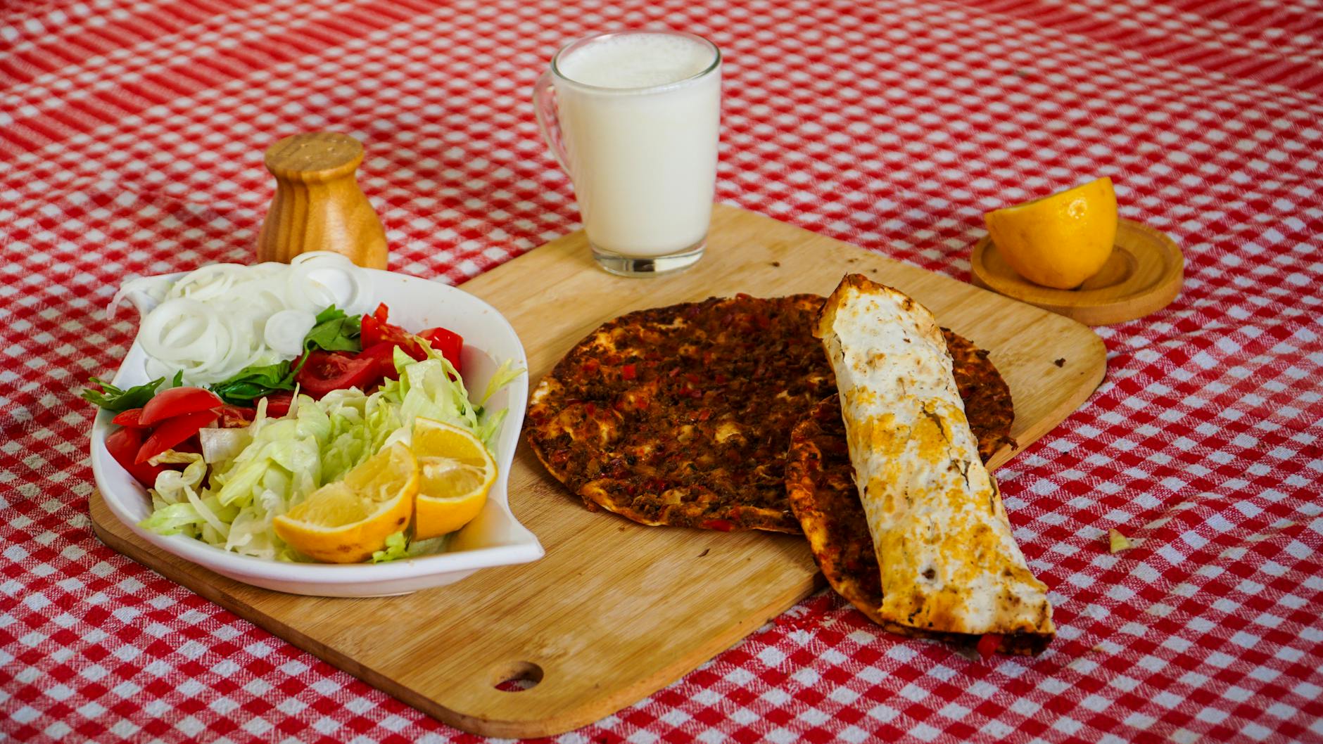 Menú completo de lahmacun con ensalada fresca y un vaso de ayran frío.