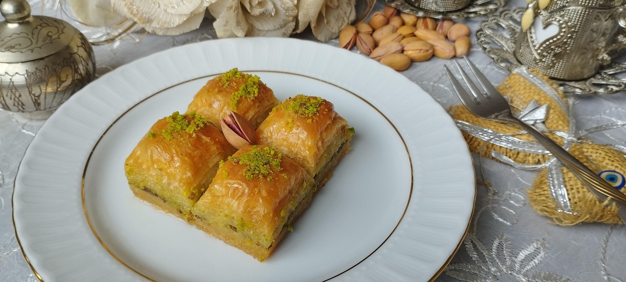 Cuatro piezas de baklava artesanal con pistacho servidas en un plato blanco.