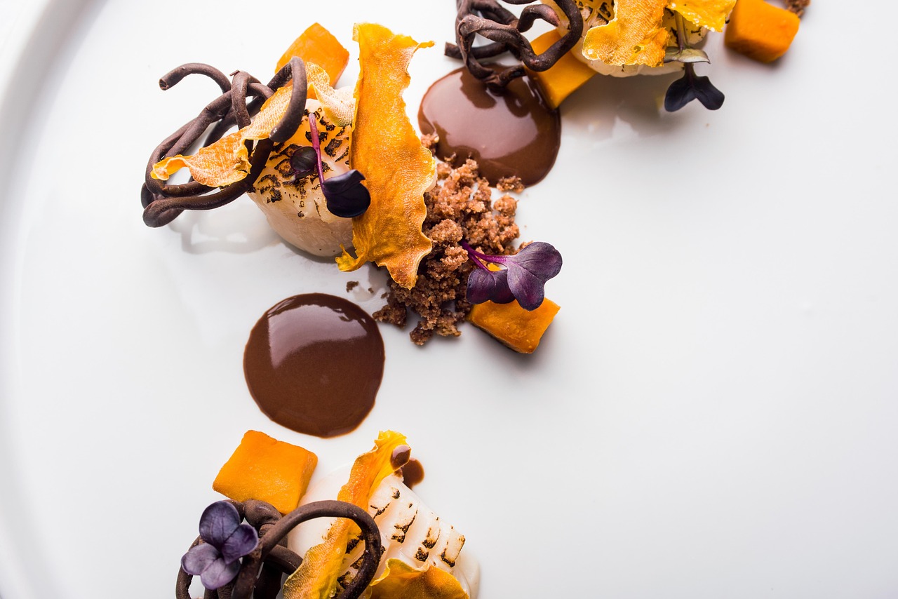 Plato de vieiras con guarnición creativa típico de la guía Michelin.