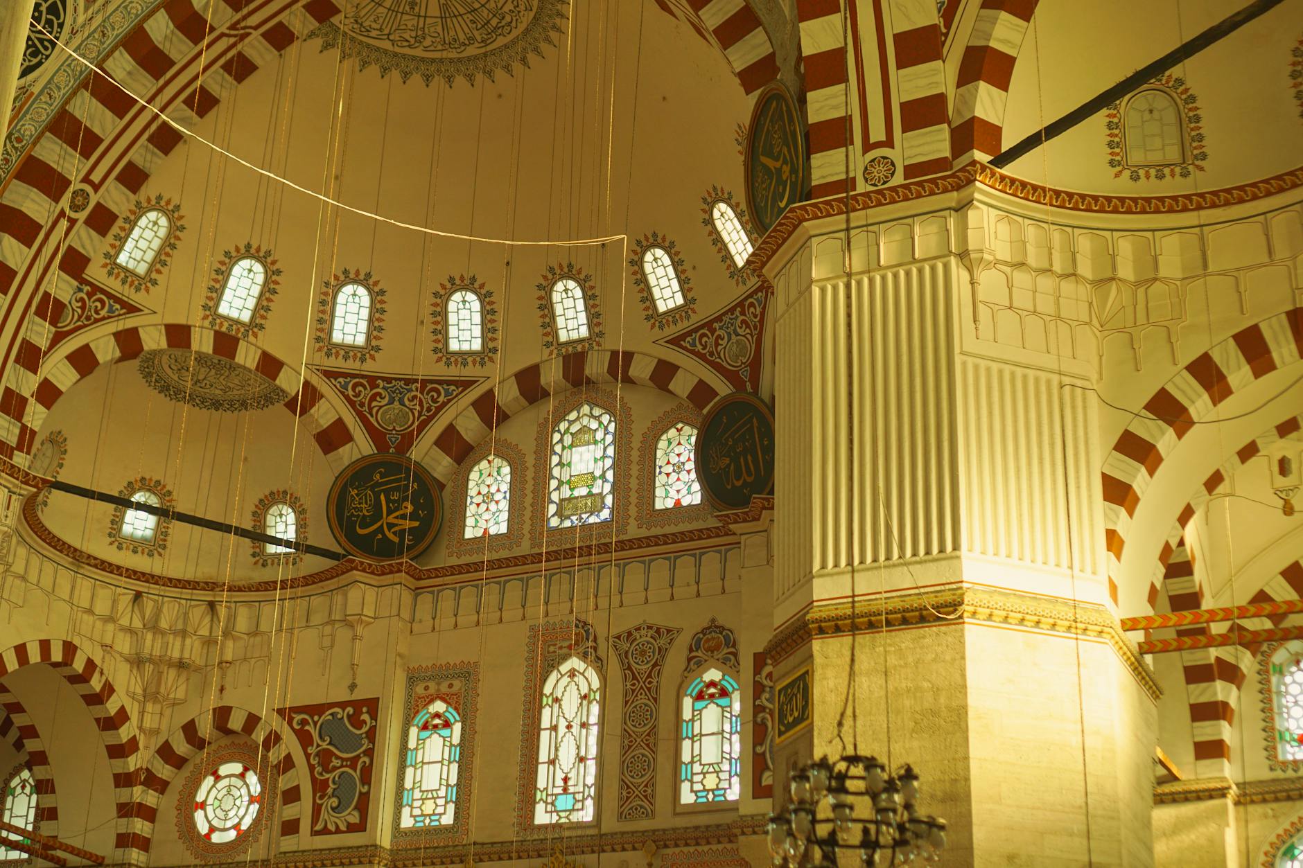 Impresionante interior de la Mezquita de Şehzade con arcos de colores y vidrieras.