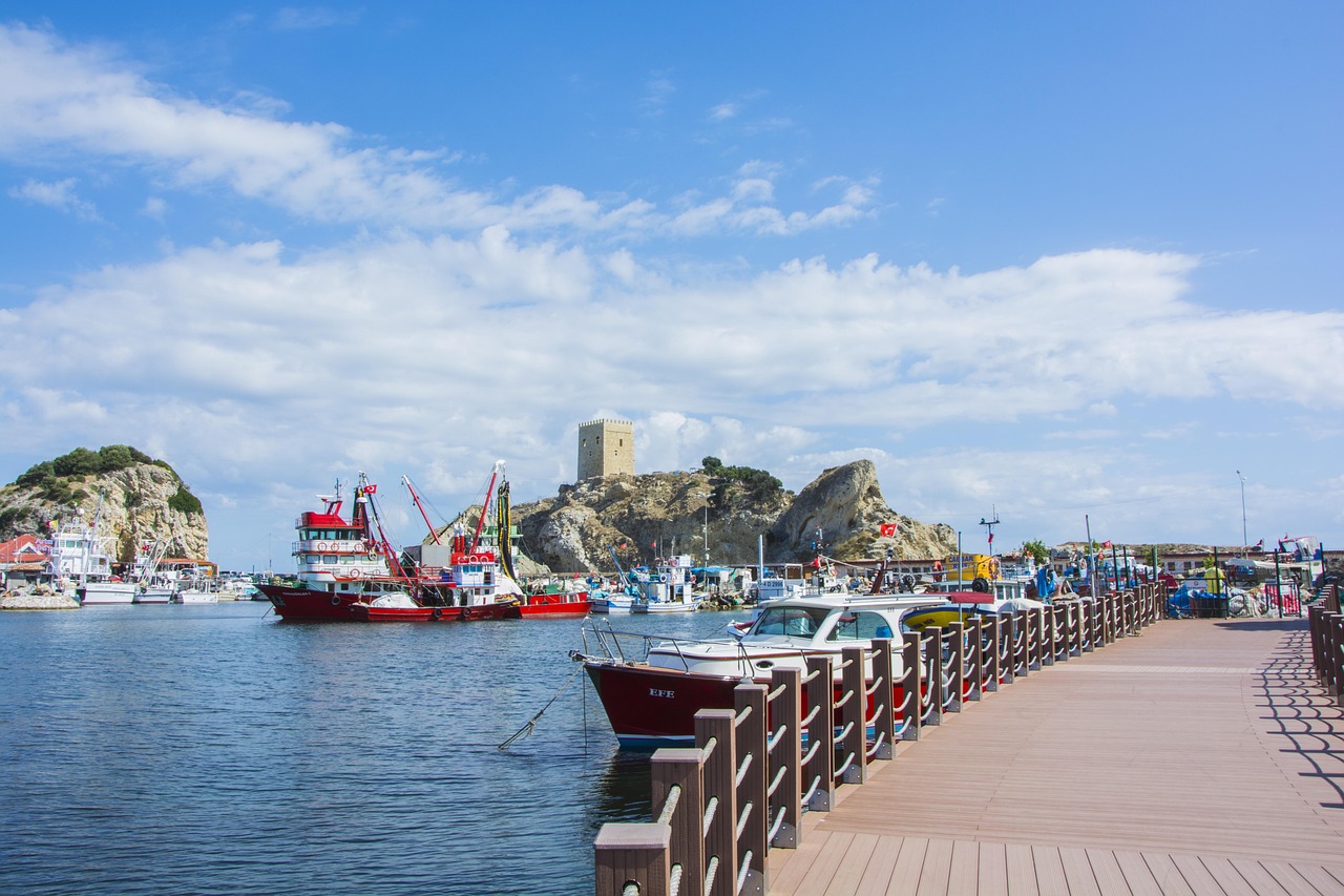 Puerto pesquero con barcos de colores y el castillo de Şile al fondo.