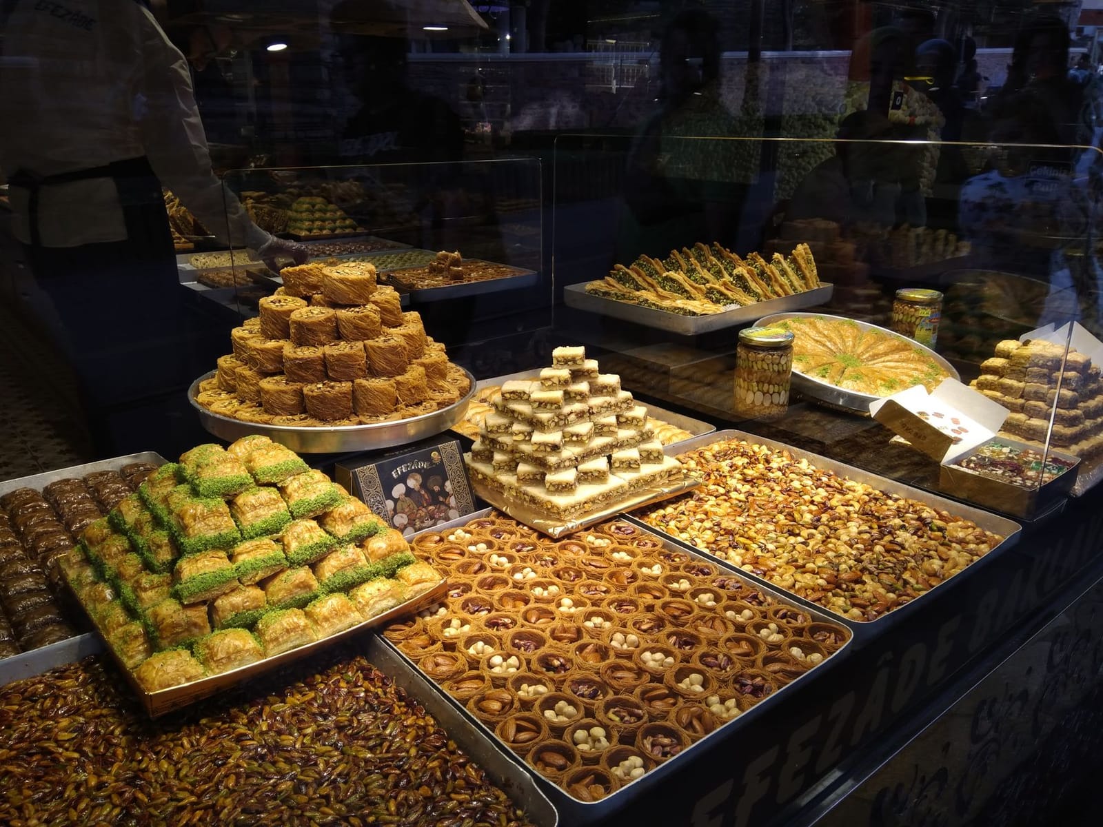 Variedad de baklava y dulces orientales expuestos en el escaparate de una tienda.