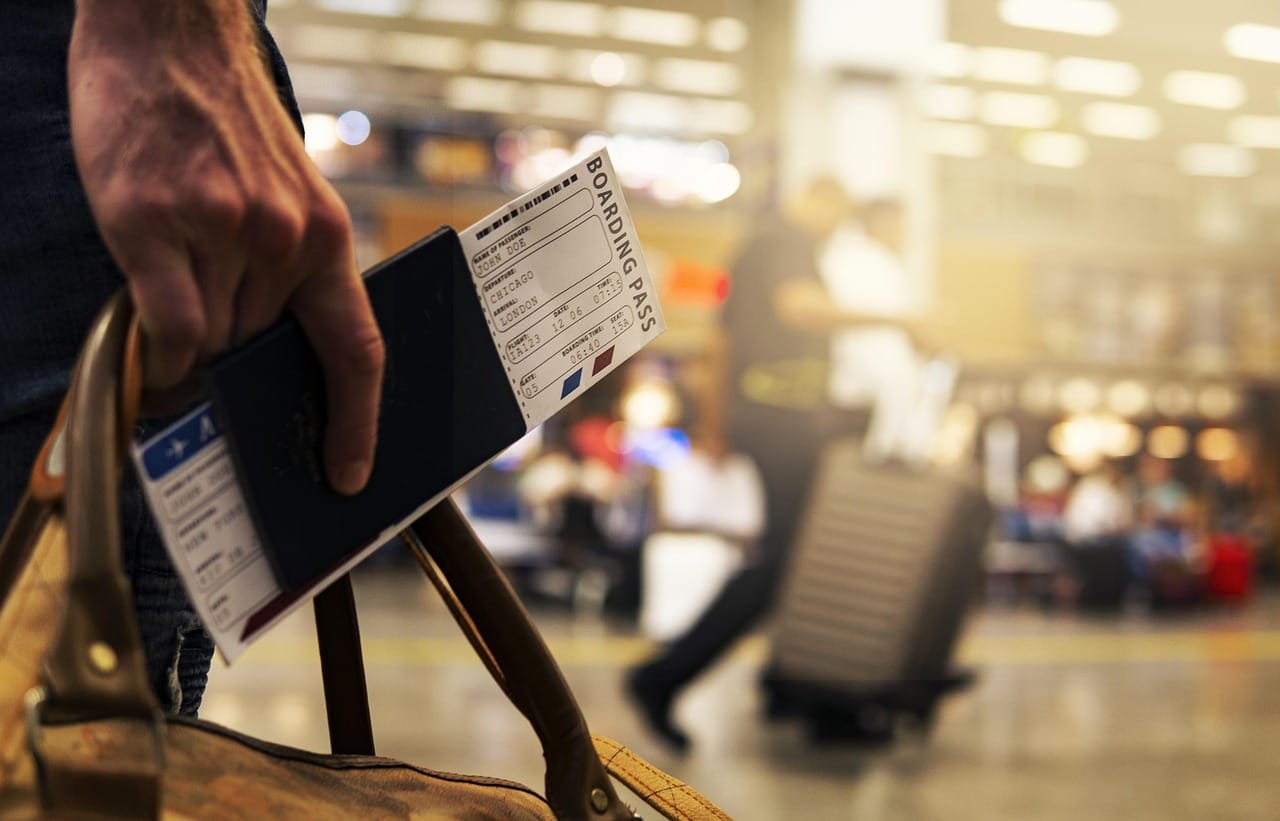 Pasajero en la terminal del aeropuerto sosteniendo su pasaporte y billete.