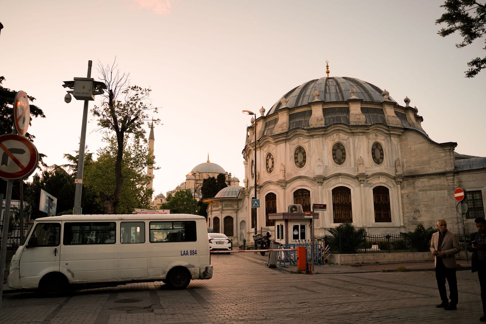 Minibús blanco circulando junto a un edificio histórico otomano en Estambul.