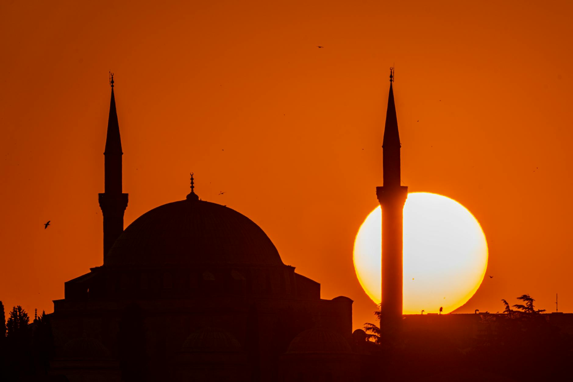 Silueta de la Mezquita Yavuz Sultan Selim durante un atardecer naranja intenso.